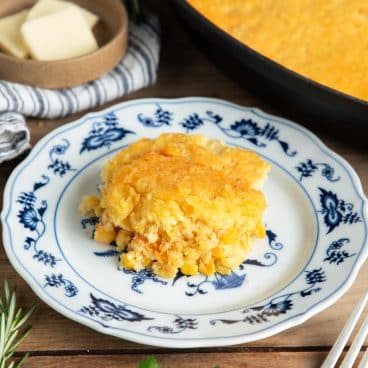 Square close up of Jiffy corn casserole on a blue and white plate.