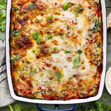 Square overhead shot of a pan of baked ravioli lasagna with ricotta and spinach.