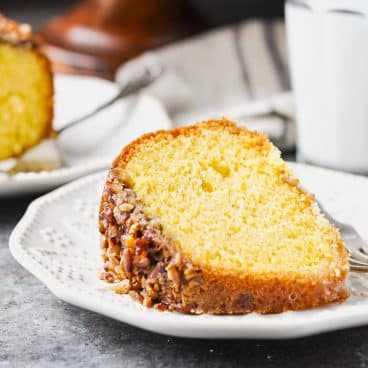 Square close up shot of a slice of rum cake on a white plate.
