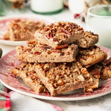 Square side shot of a vintage red and white plate full of pecan bars.