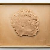 Dough for pecan bars on a parchment lined baking sheet.