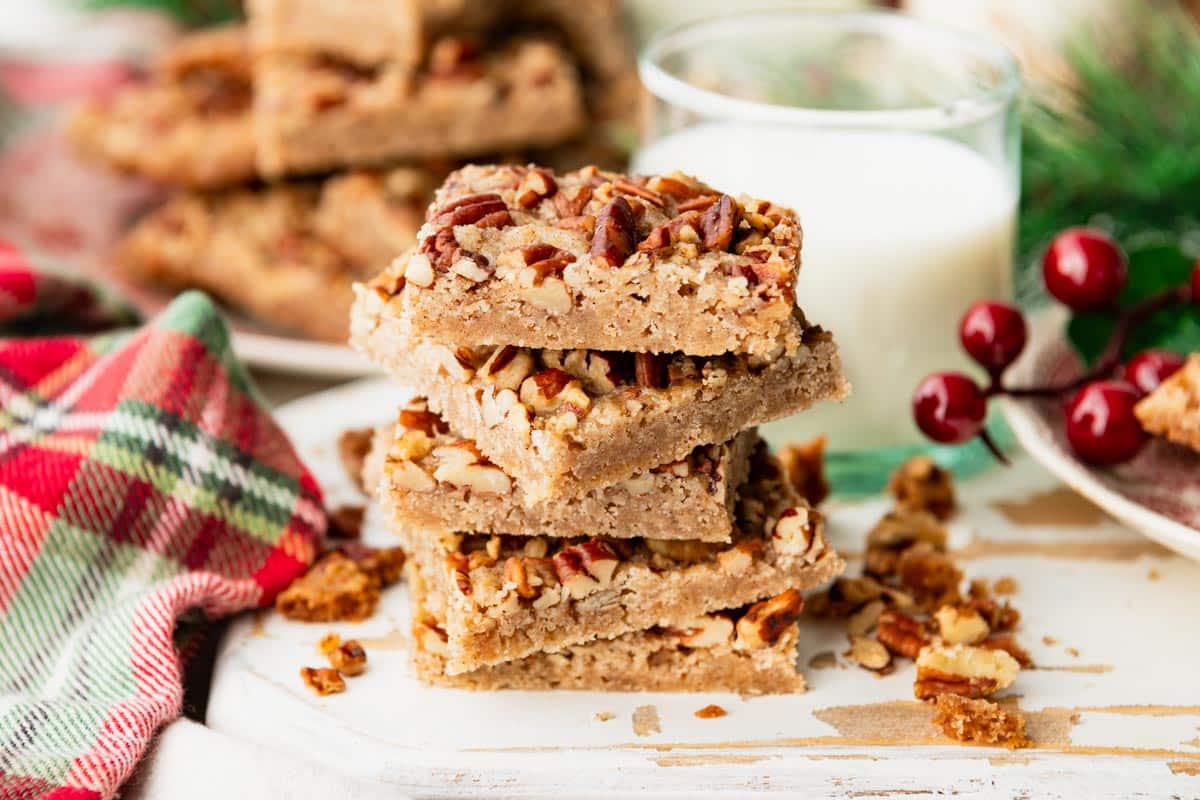 Horizontal side shot of cinnamon pecan cookie bars on a white cutting board.