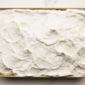 Adding Cool Whip and coconut to the top of the cake.