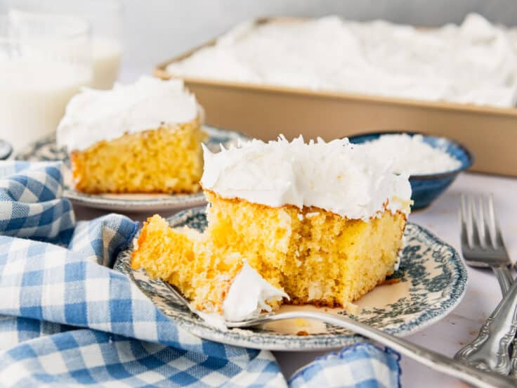 Horizontal side shot of two slices of coconut cream cake on small blue plates.