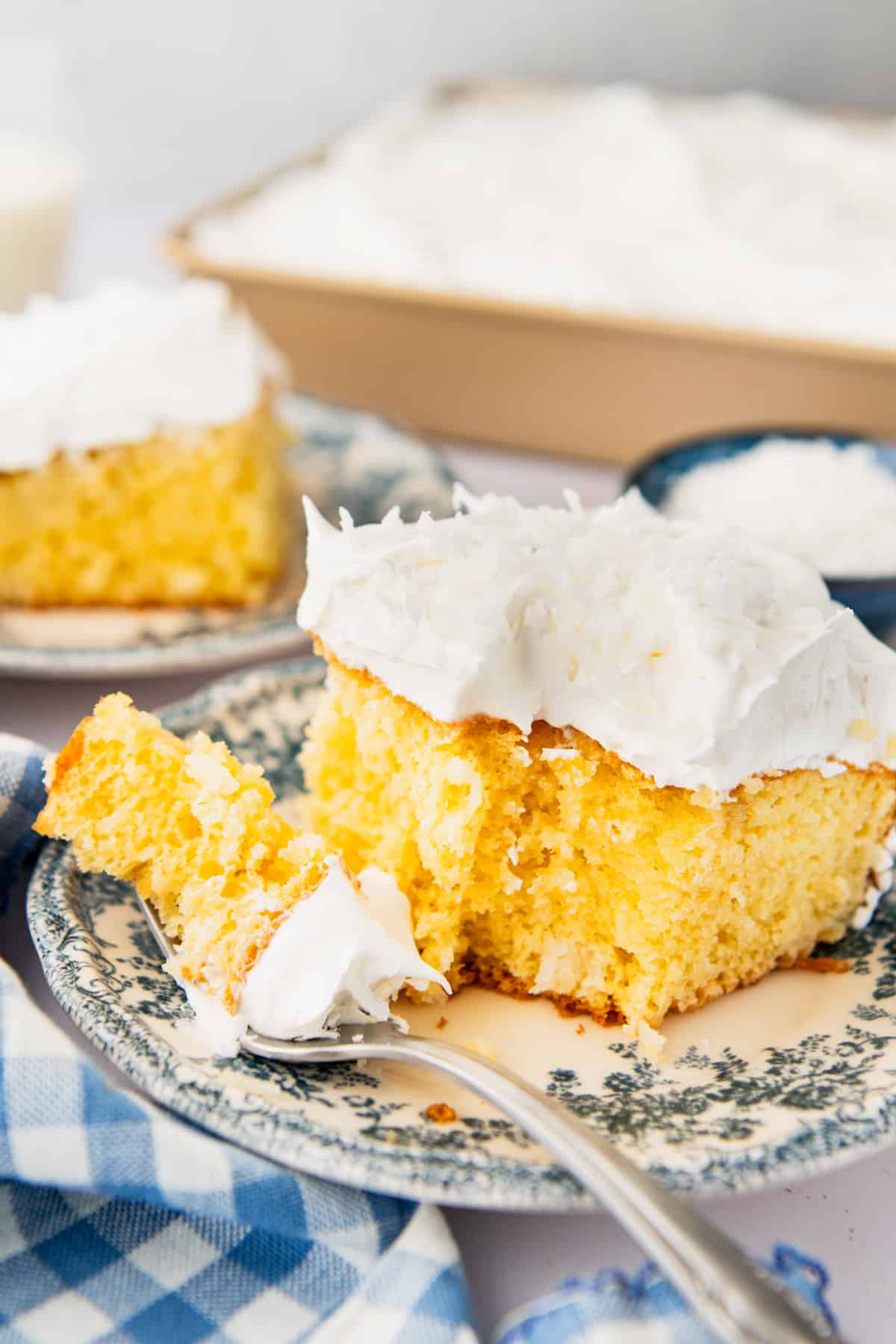 Side shot of a bite of coconut cream poke cake on a fork on a small plate.