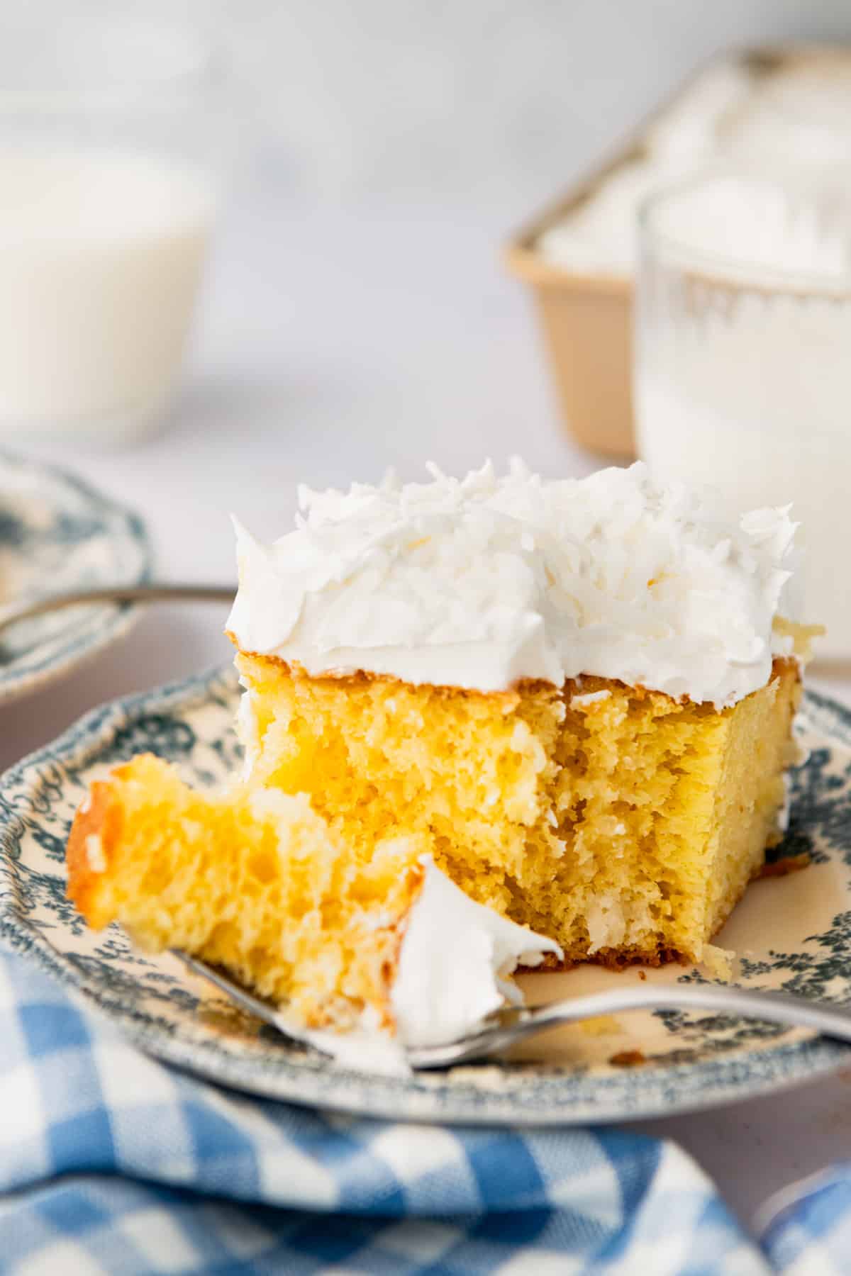 Side shot of a fork taking a bite of coconut cream poke cake.