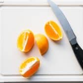 Quartered mandarin orange on a white cutting board.