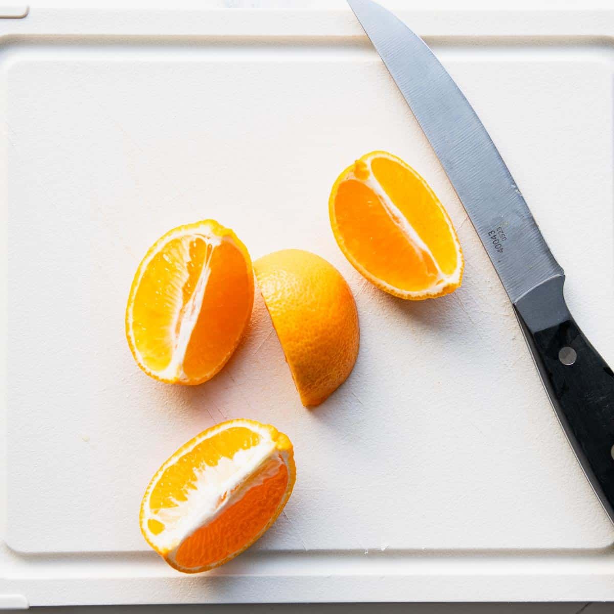 Quartered mandarin orange on a white cutting board.