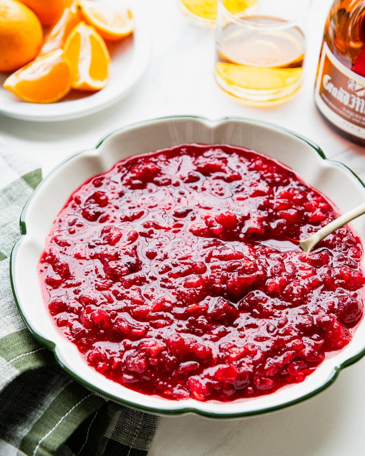 Spoon in a bowl of cranberry orange relish on a white table.