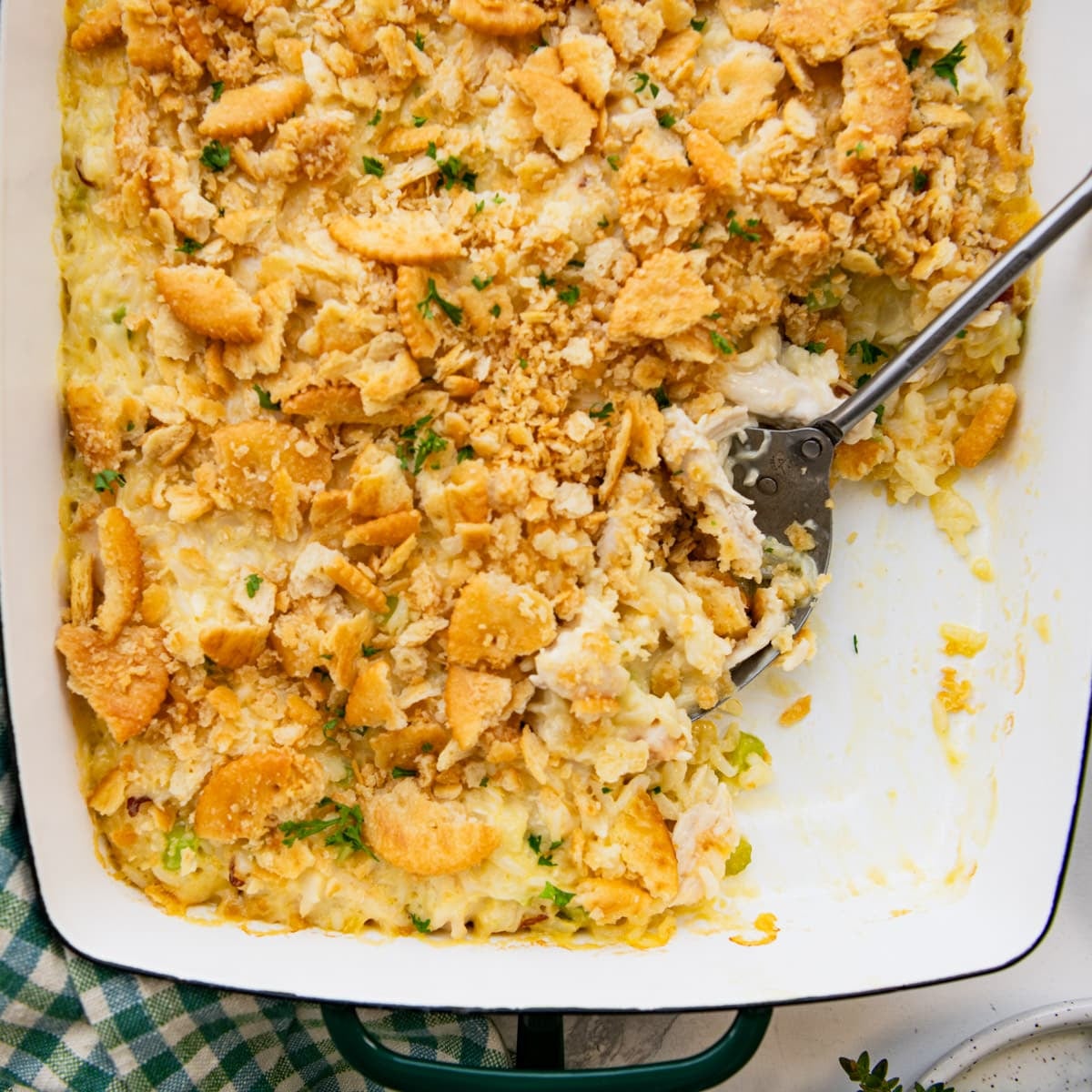 Square overhead image of a serving spoon in a pan of old fashioned chicken and rice casserole.