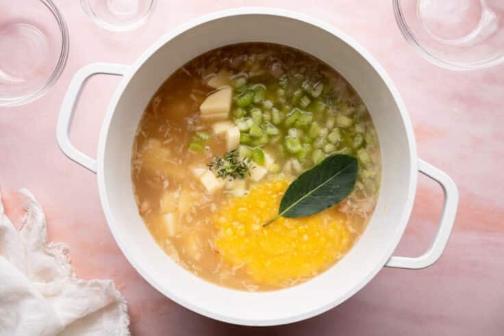 Adding vegetables and seasoning to the broth mixture.