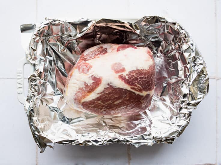 Pork shoulder roast in a foil lined pan before cooking.
