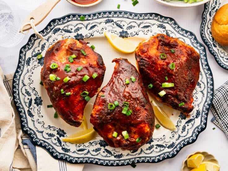 Horizontal overhead shot of baked bbq chicken breast on a blue and white serving platter.