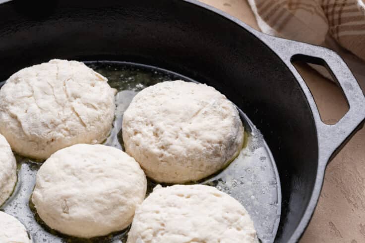 Arranging 7up biscuits in a cast iron skillet before baking.