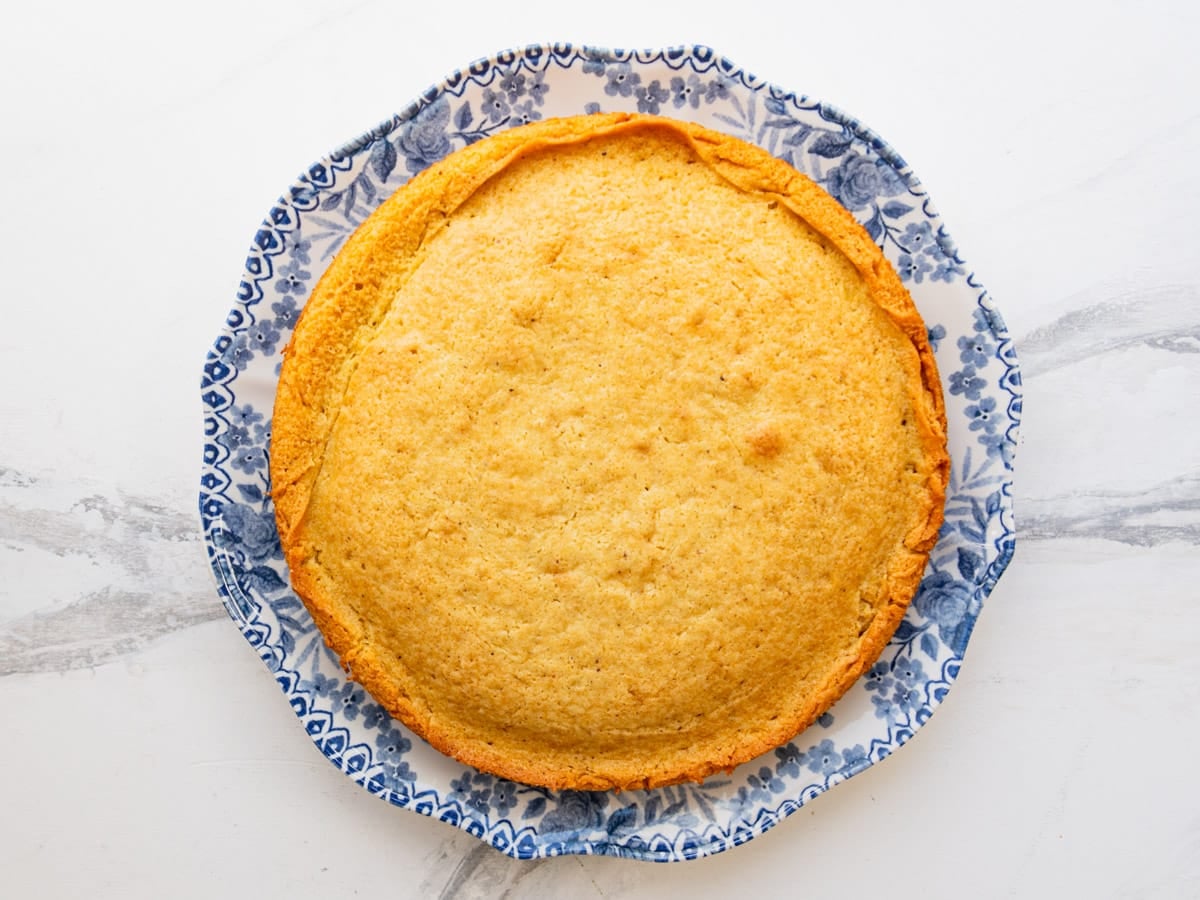 Overhead shot of a baked breakfast cake on a serving plate before slicing.