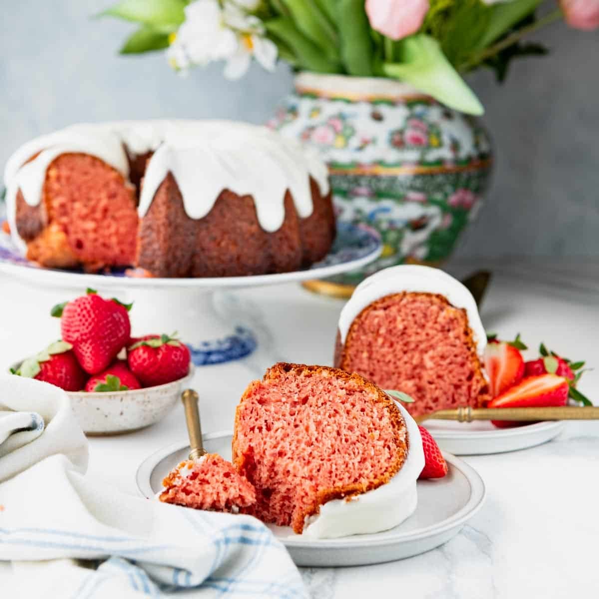 Square front shot of slices of strawberry bundt cake on a white table.