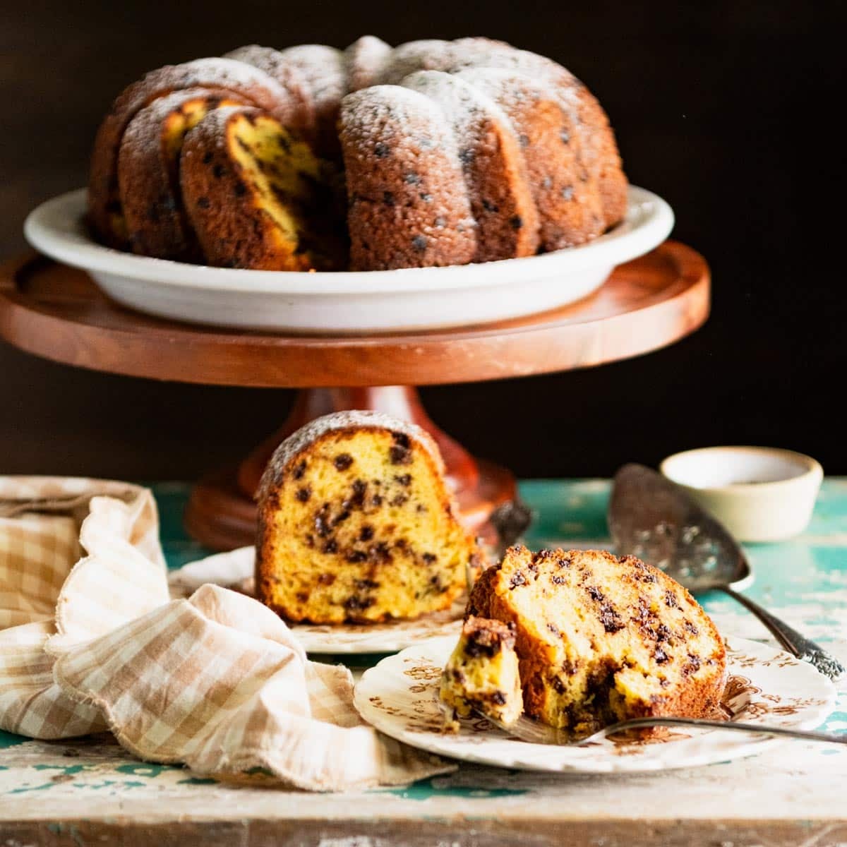 Slices of chocolate chip bundt cake on plates on a rustic wooden table.