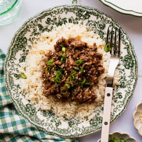 Square overhead shot of a green and white bowl full of white rice and teriyaki ground beef.