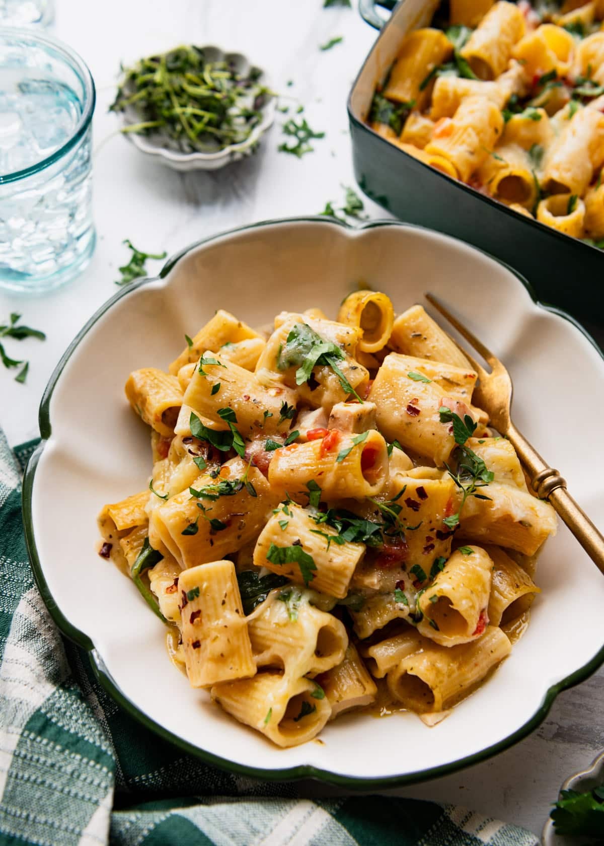 Side shot of a bowl of chicken pesto pasta alfredo on a table.