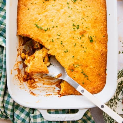 Square overhead shot of a pulled pork casserole with a cornbread crust in a white baking dish.