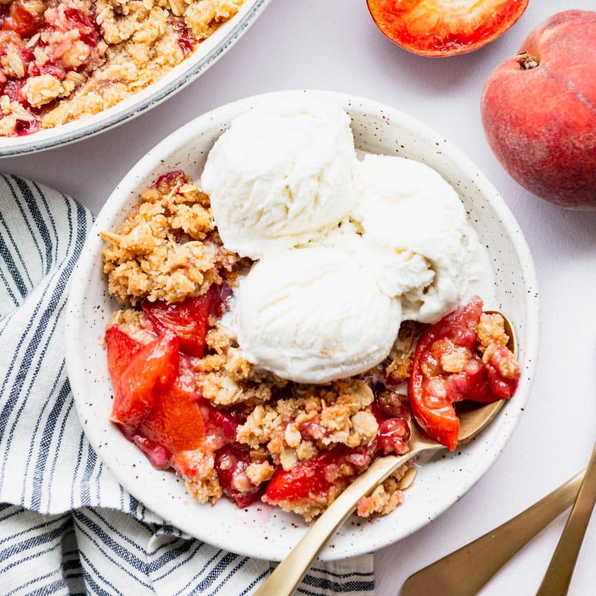 Square overhead image of a warm bowl of peach crisp with vanilla ice cream on top.
