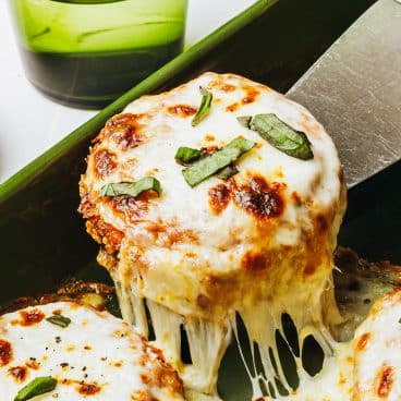 Square close up shot of baked eggplant parmesan on a server.