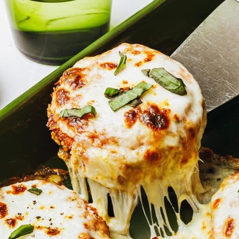 Square close up shot of baked eggplant parmesan on a server.