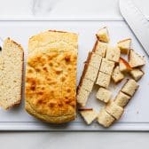 Cubed Southern cornbread on a white cutting board.