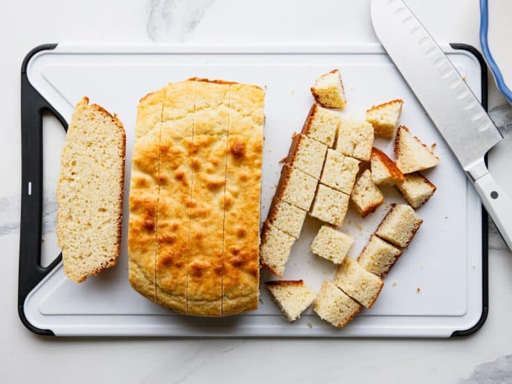 Cubed Southern cornbread on a white cutting board.
