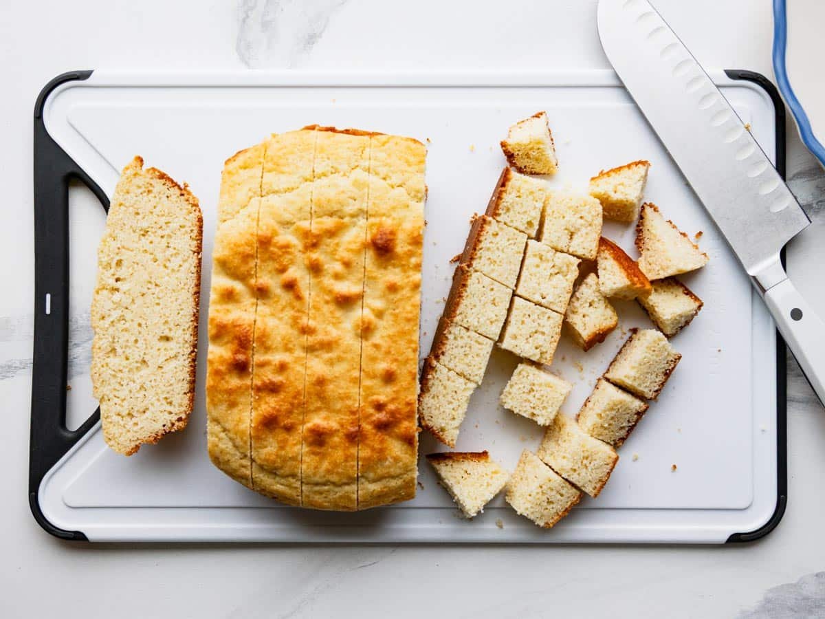 Cubed Southern cornbread on a white cutting board.