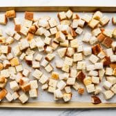 Toasted bread cubes and cornbread cubes on a baking sheet.