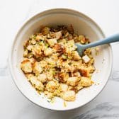Process shot showing how to make cornbread dressing in a white mixing bowl.