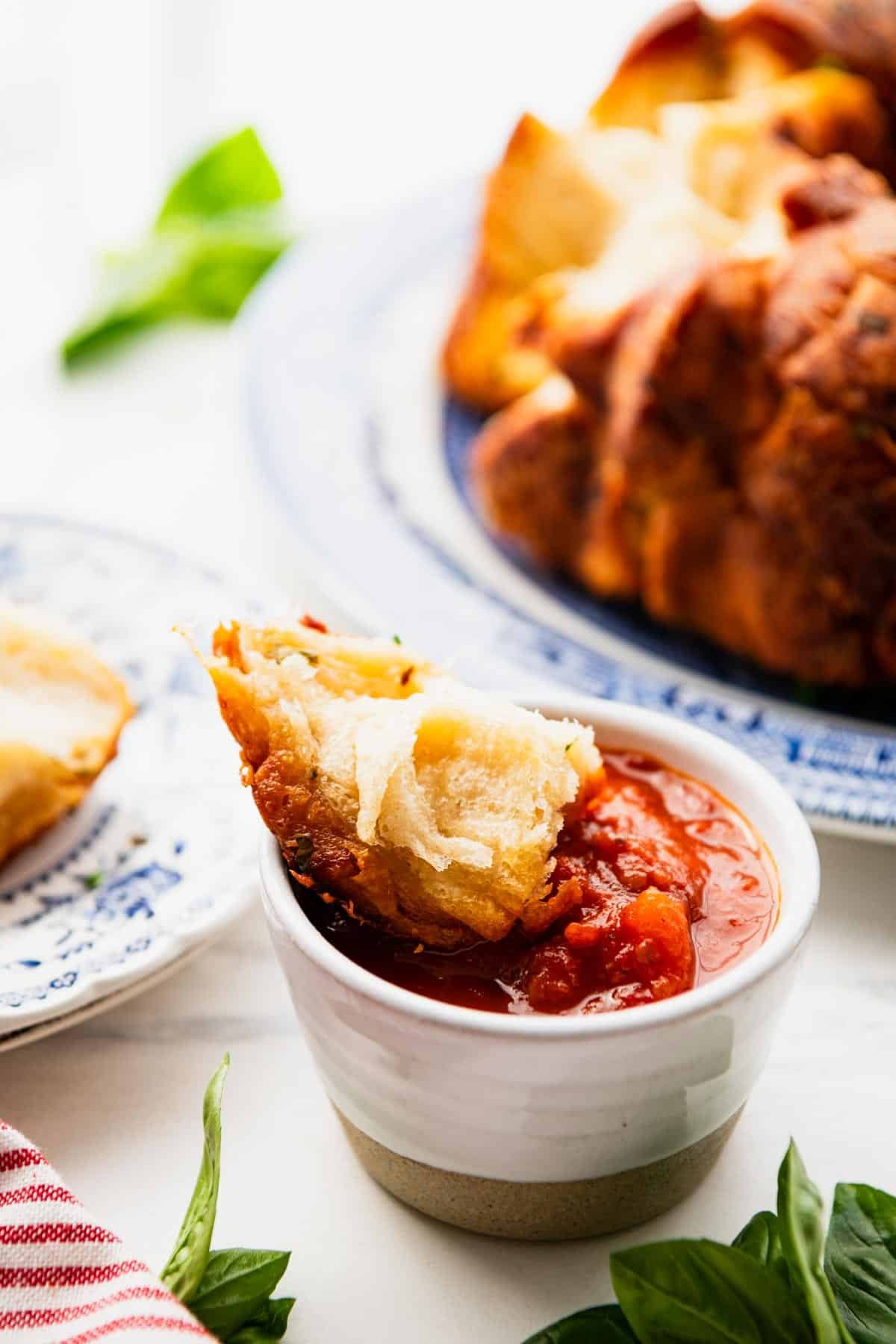 Hunk of pull apart garlic bread in marinara dip.