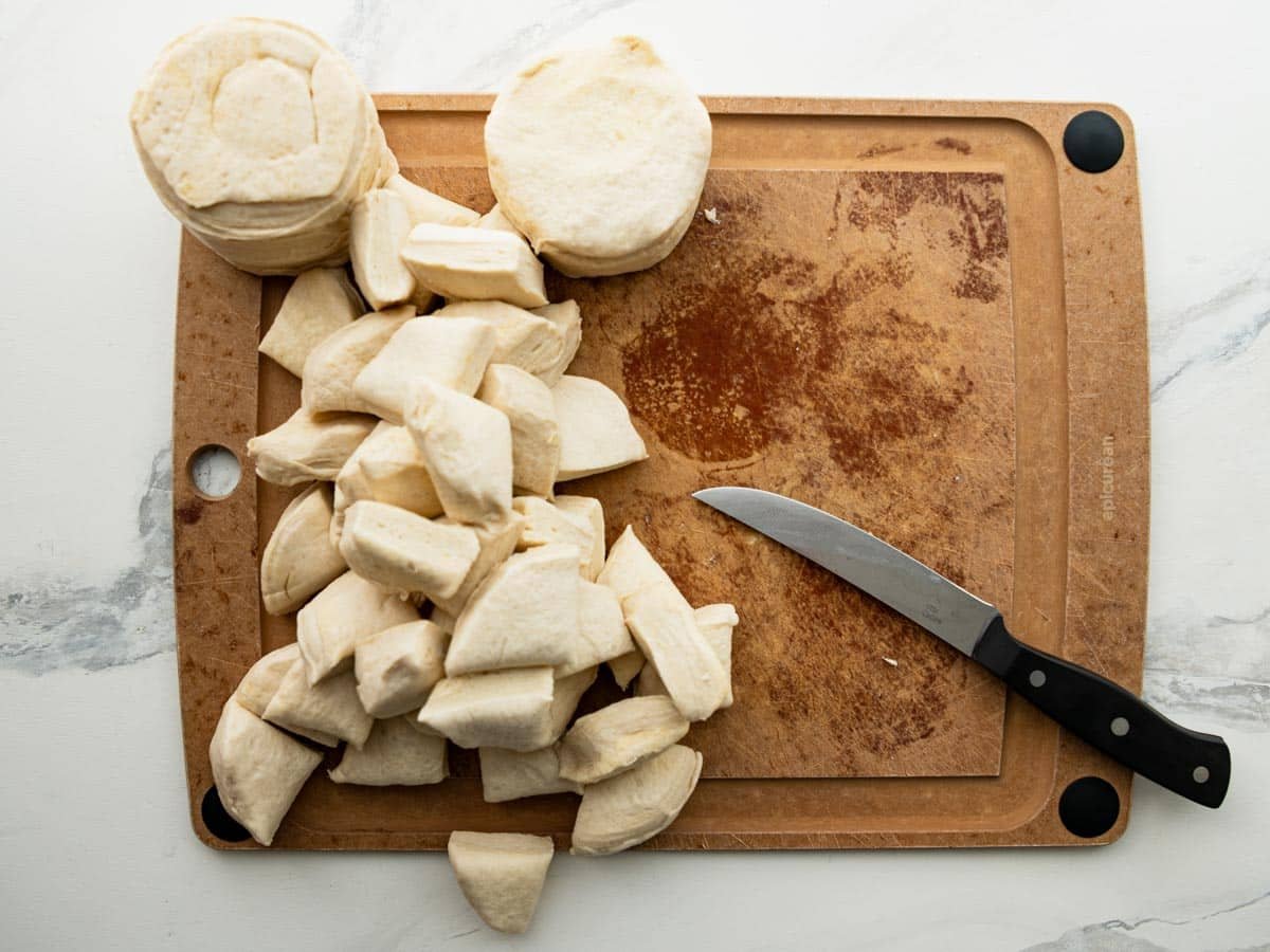 Quartering biscuit dough on a cutting board.
