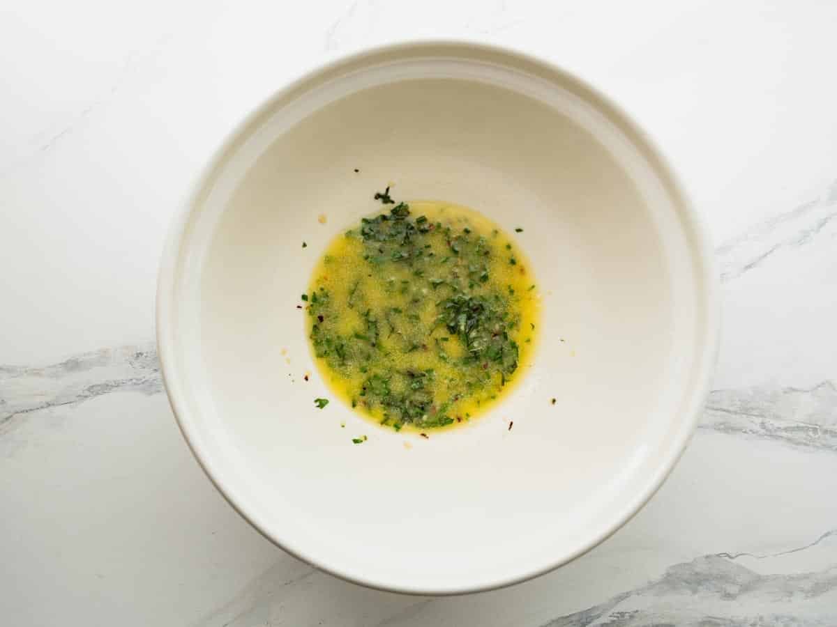 Melted butter and herbs in a bowl.