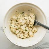 Tossing ingredients for pull apart garlic bread in a bowl.