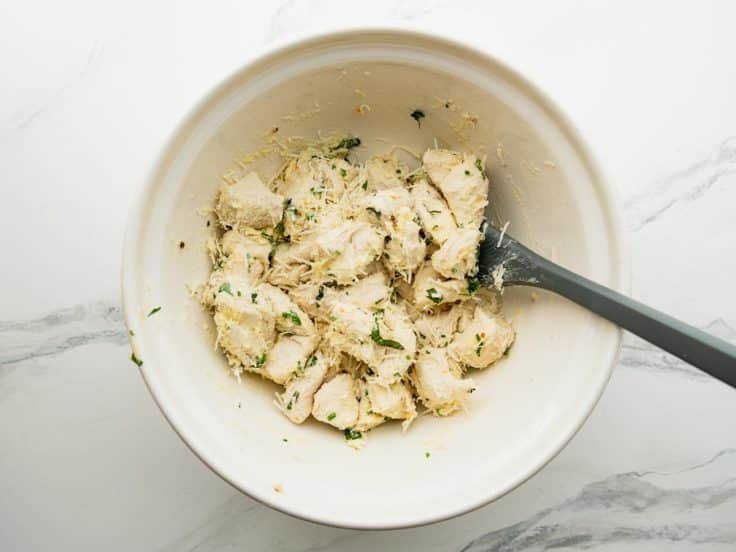 Tossing ingredients for pull apart garlic bread in a bowl.