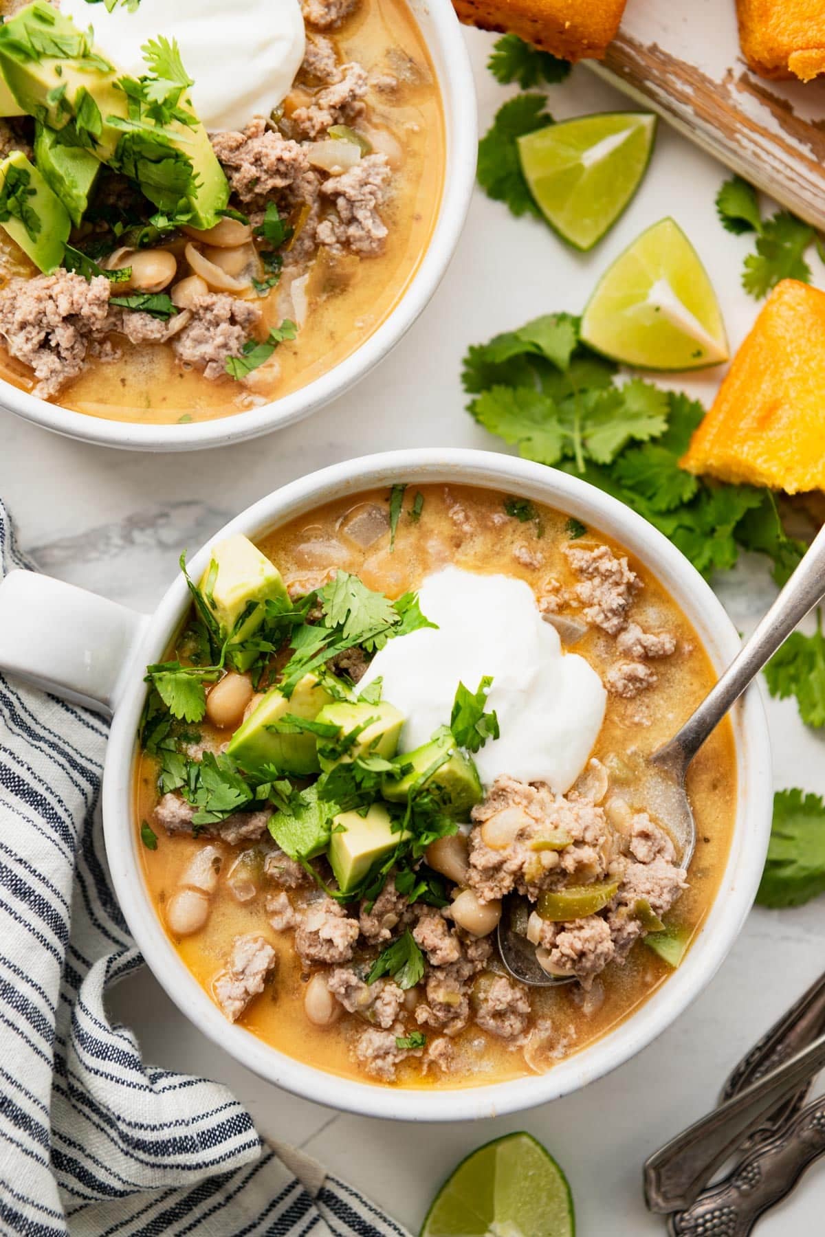Overhead image of two bowls of white turkey chili on a white table.