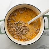 Ladle in a Dutch oven full of creamy white turkey chili.