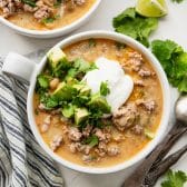 Horizontal overhead image of a bowl of white ground turkey chili with toppings.