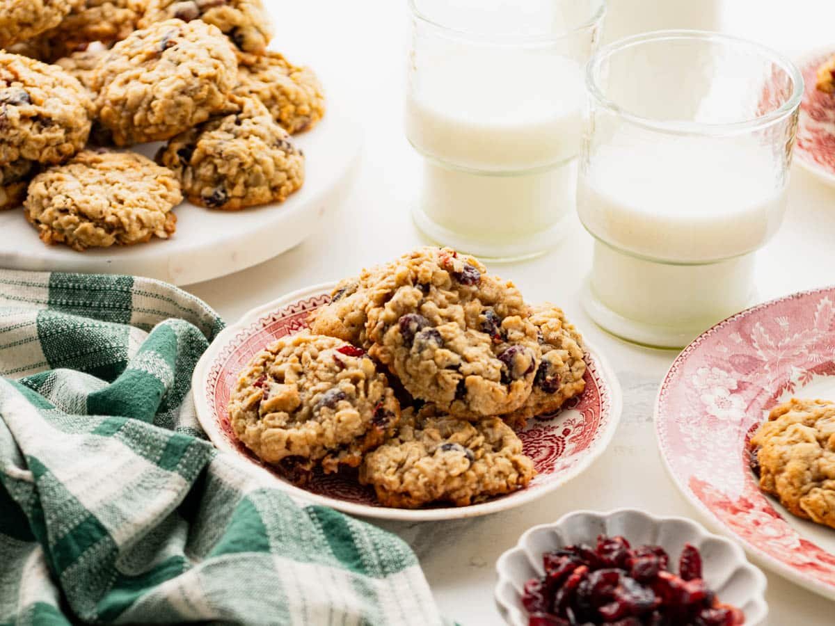 Horizontal side shot of thick and chewy cranberry oatmeal cookies on a white table.