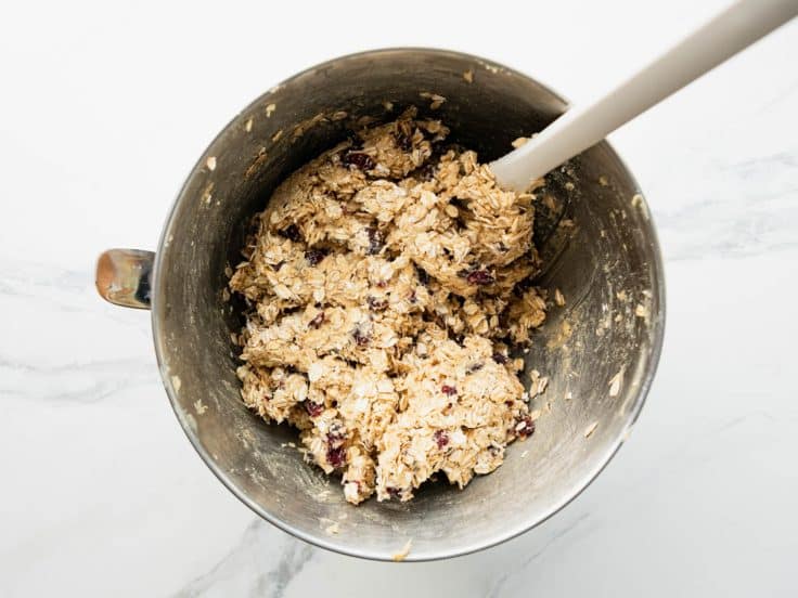 Stirring oats and cranberries into dough.