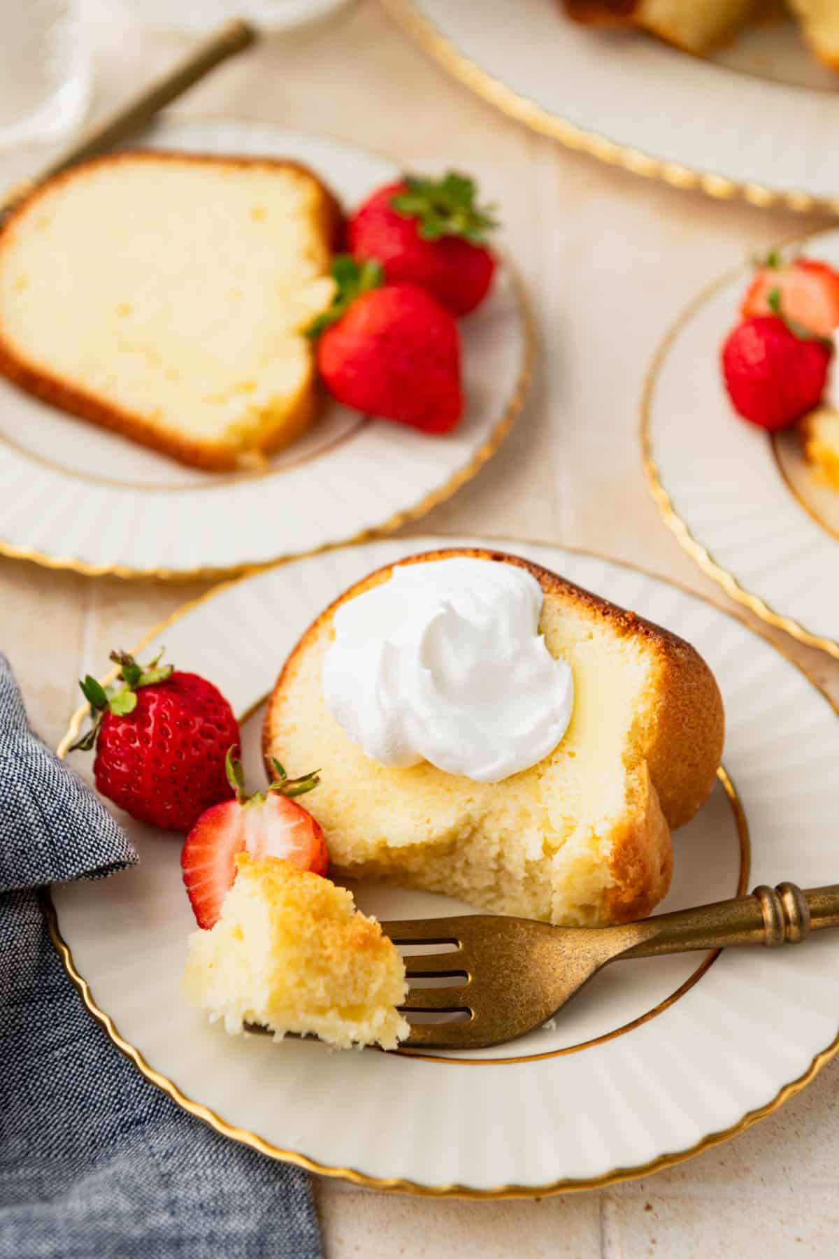 Slice of buttermilk pound cake on a plate with a dollop of whipped cream and fresh berries.
