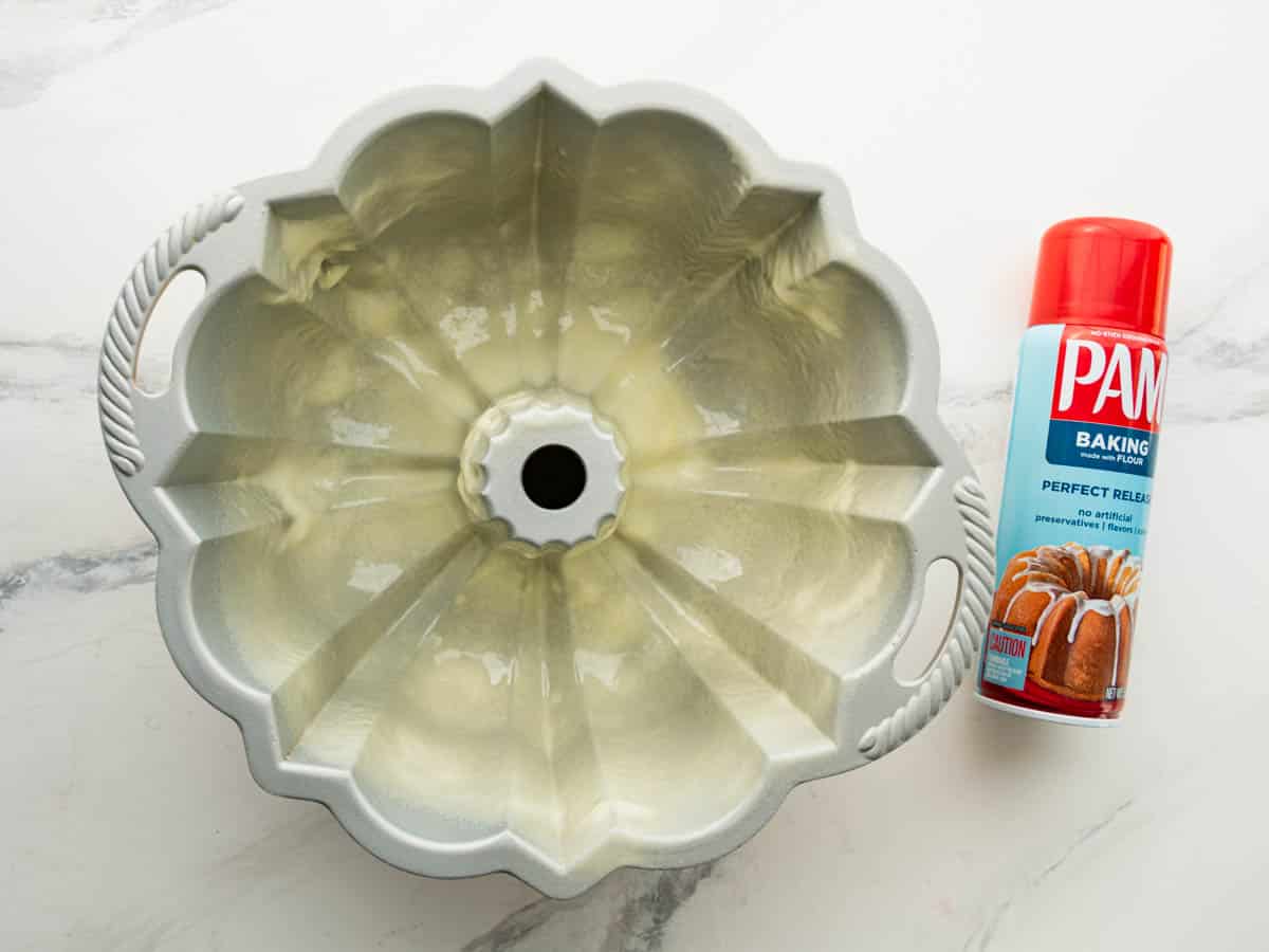 Greasing and flouring a bundt pan with nonstick baking spray.