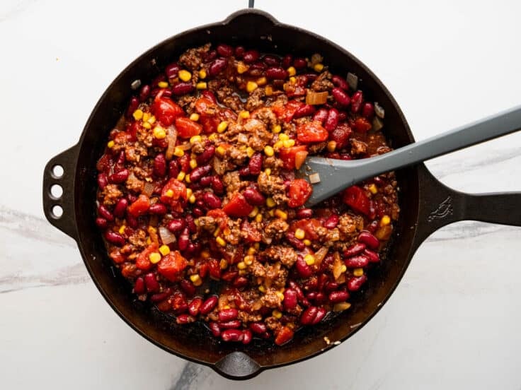 Ingredients for chili filling in a cast iron pan.