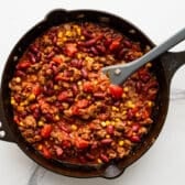 Process shot showing how to make the chili for a casserole in a cast iron skillet.