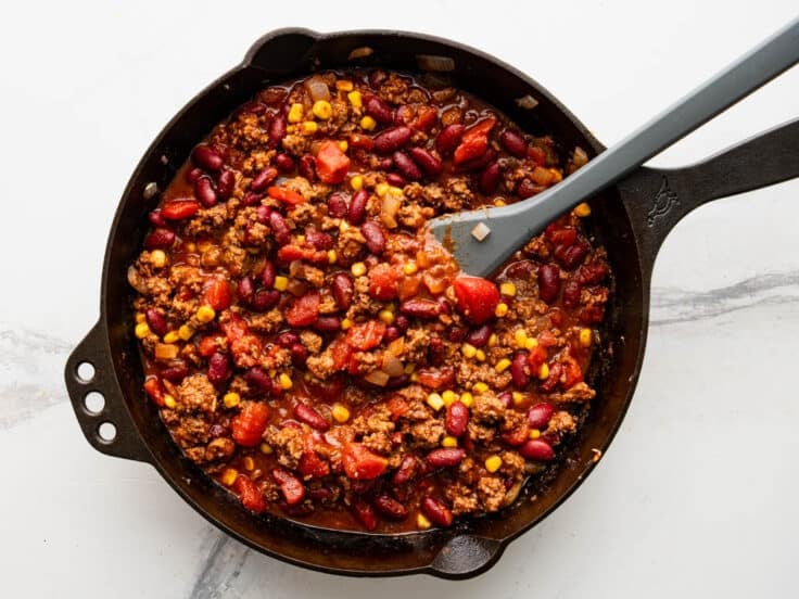 Process shot showing how to make the chili for a casserole in a cast iron skillet.