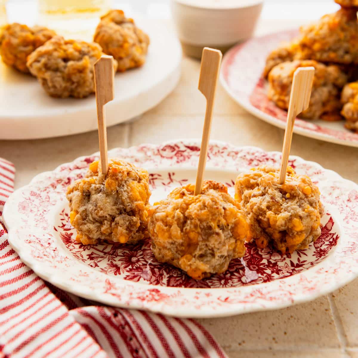 Square side shot of three cream cheese sausage balls with toothpicks on a small plate.