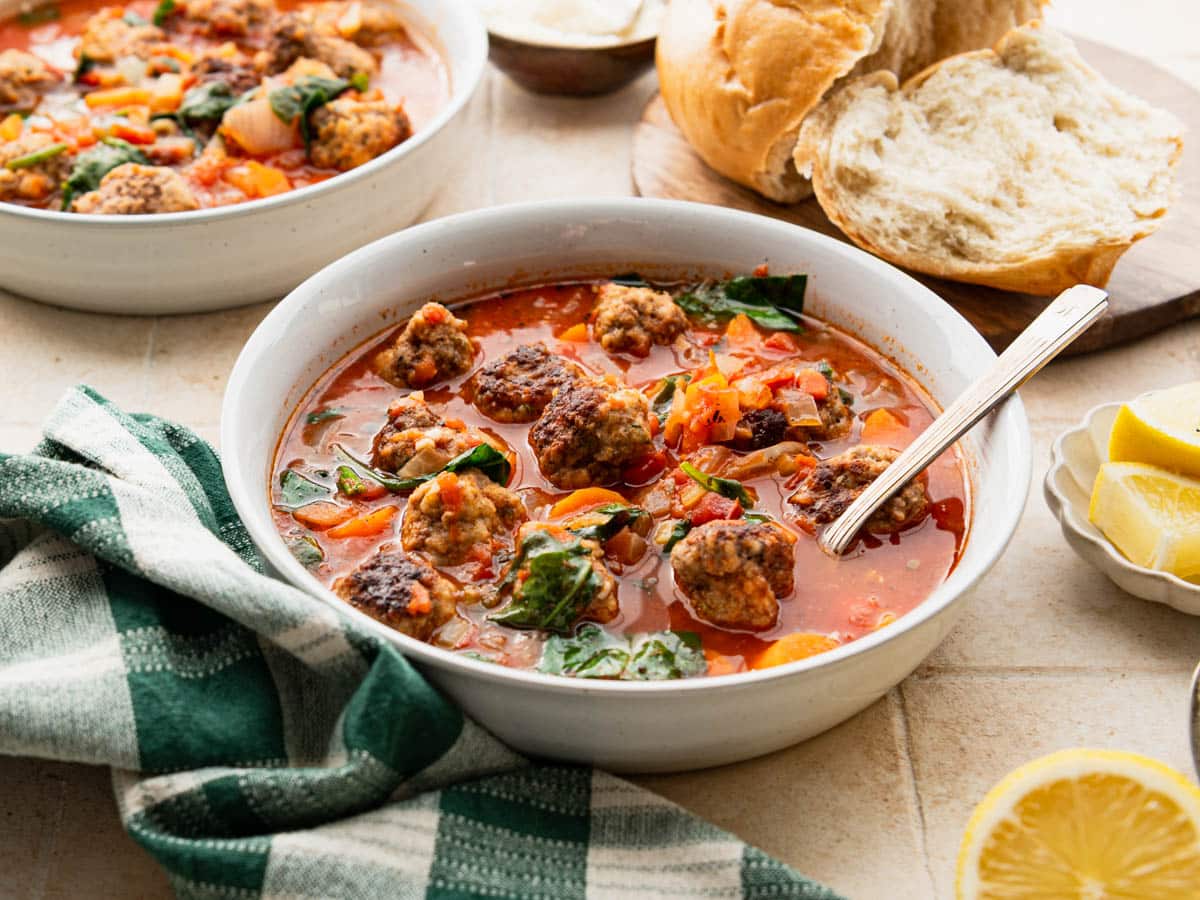 Horizontal side shot of bowls of meatball soup on a dinner table.