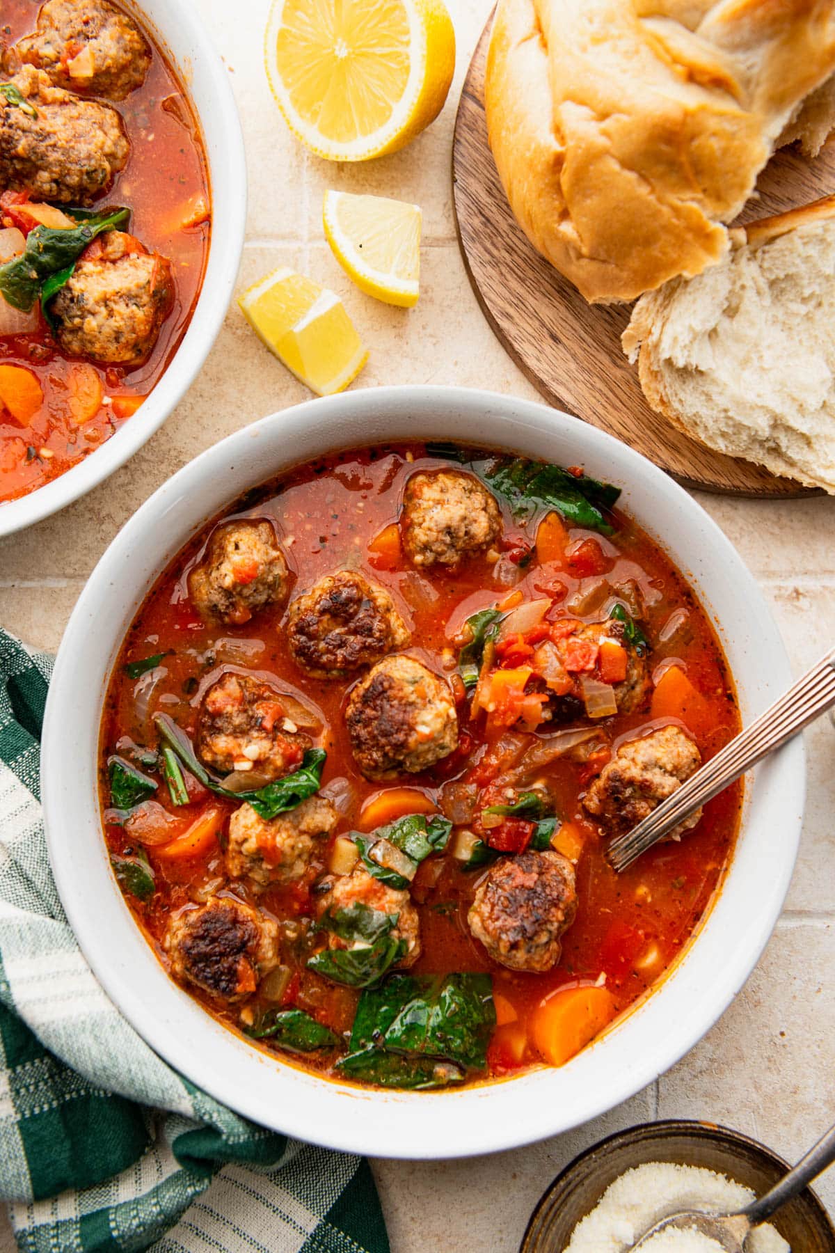 Overhead shot of two bowls of meatball soup on a table with bread.